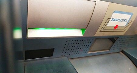 The green light lights up in the hole where the transaction receipt paper comes out of the ATM...