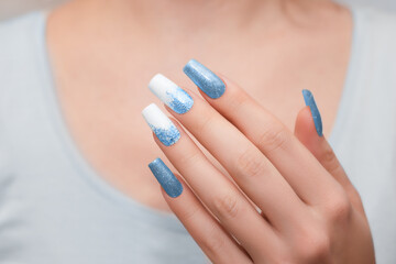 Female hands with long nails with glitter nail polish. Long blue nail design. Women hand with sparkle manicure.