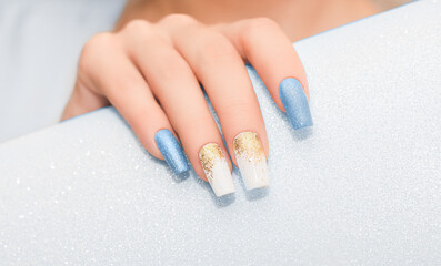 Obraz na płótnie Canvas Female hand with long nails with glitter nail polish. Long blue nail design. Women hand with sparkle manicure on glitter background