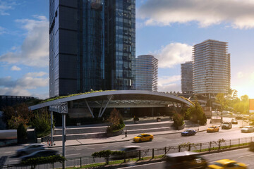 Passenger cars drive quickly along the road in the city against the backdrop of skyscrapers.