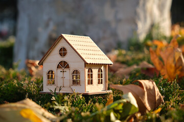 Beautiful wooden toy house in the autumn forest with yellow leaves.