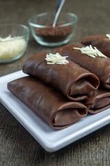 dadar gulung pisang coklat keju or chocolate cheese banana roll omelette served on a white plate with a dark background