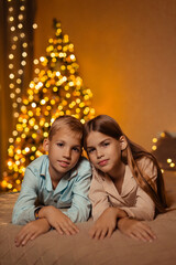 Fototapeta na wymiar Twins boy and girl, brother and sister, at home waiting for the New Year holiday in the bedroom on the bed