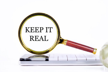 KEEP IT REAL lettering through a magnifying glass on a calculator and part of a magic ball in the...
