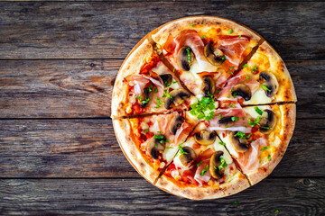 Top view of pizza speck with ham, mozzarella cheese and white mushrooms on wooden table 