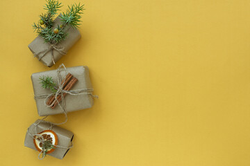 Zero waste Christmas concept. Natural gift materials paper fir branches dried citrus cinnamon on a yellow background. Flat layout top view. Eco-greeting card in pastel colors. Gifts New Year 2024