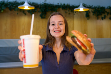 Portrait of young happy woman or beautiful teenager girl eating fast junk food, tasty burger and...