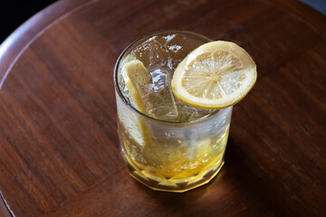 Iced honey lemon soda on wooden table with sunlight through a window.