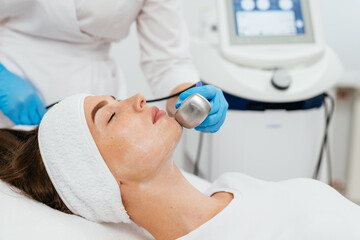 Cosmetologically ultrasonic facelift. A young woman enjoys a procedure at a cosmetology beauty center. Facelift, youth and healthy skin.