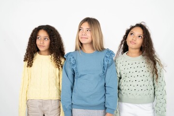 Three beautiful multiracial kid girls  looking aside into empty space thoughtful