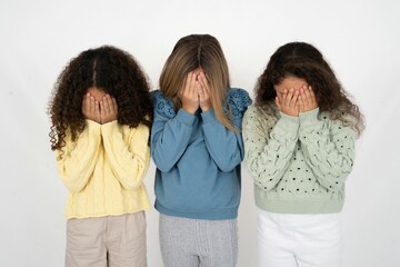 Three beautiful multiracial kid girls  covering her face with her hands, being devastated and crying. Sad concept