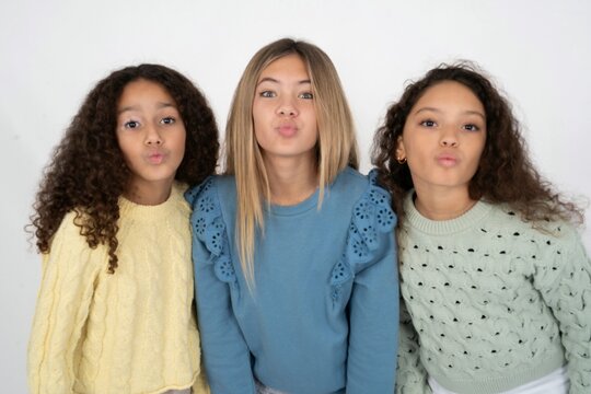 Shot of pleasant looking Three beautiful multiracial kid girls  , pouts lips, looks at camera, Human facial expressions