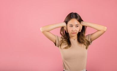 Asian portrait beautiful young woman have close ears with hand palms and close eyes, studio shot isolated on pink background, Thai female covering ears for loud noise with copy space, bad pressure - obrazy, fototapety, plakaty