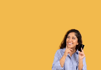 Cheerful pensive latin millennial brunette woman in casual show credit card, think at sale