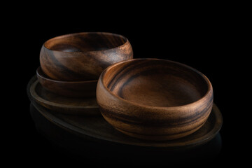 Empty wooden round acacia bowls on a wooden hevea tray on a black background. Handmade wooden utensils. Eco-friendly. Natural. Selective focus. Horizontal. Close-up.