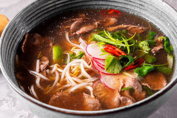Soup Pho Bo in bowl on gray stone table