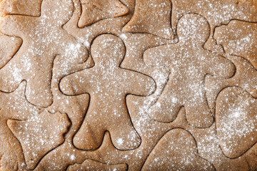Cooking ginger cookies, Christmas and New Year traditional cookies in shape of gingerbread man, raw rolled out dough with cut out dough figures, closeup texture, top view, pattern on dough, above
