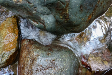 Close-up of a stone in the river with water flowing.