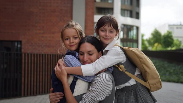 Hard-working, ambitious mother preparing daughters for school, saying goodbye to them in front of the school building, and heads to work. Concept of work-life balance for women.