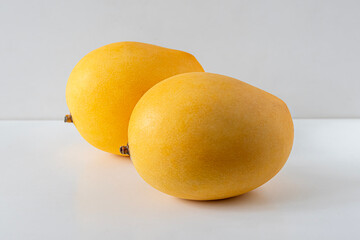 Yellow ripe sweet mangoes on a light background