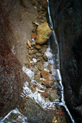 Stream in the forest with stones and clear water, close-up
