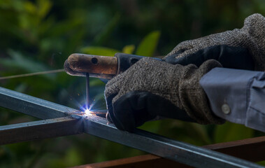 Welder welding galvanized iron frame with proper protection outdoor SMAW