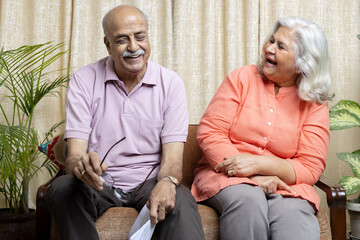 Happy indian senior,couple looking in to the policy papers and smiling, After Retirement policy...