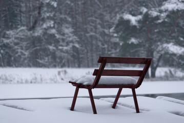 Fototapeta premium WINTER ATTACK - A bench and a fishing pier by the lake covered with snow 