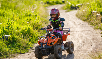 Fototapeta na wymiar A child rides a quad bike through the mud. ATV rider rides