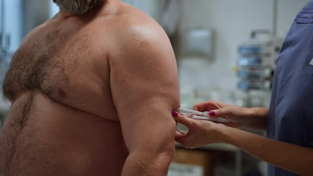 Doctor measuring arm circumference of overweight patient. Obesity affecting middle-aged men's health. Concept of health risks of overwight and obesity.