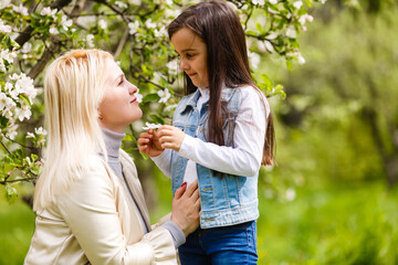 Obraz premium Happy woman and child in the blooming spring garden. Mothers day holiday concept.