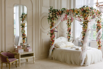 Elegant cozy bedroom in soft light colors, a large comfortable double bed with a canopy decorated...