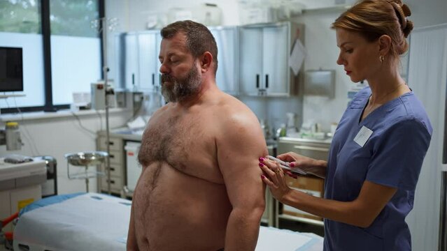 Doctor measuring arm circumference of overweight patient. Obesity affecting middle-aged men's health. Concept of health risks of overwight and obesity.