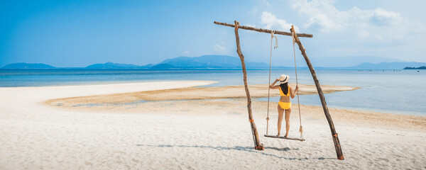 Traveler asian woman relax and travel in swing on summer beach at Koh Rap Samui in Surat Thani...