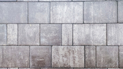  Close-up shot of a gray paved road with stone bricks and cement texture.
