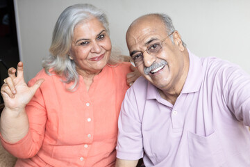 indian senior couple taking selfie with phone at living room, Retired life concept