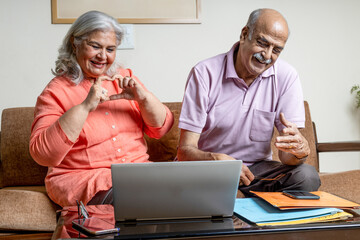 Happy Indian senior couple looking into the files and checking finance liabilities , senior...