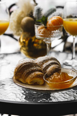 New Year's breakfast on the hotel balcony in the mountains. Coffee with croissant, juice and tangerines against the backdrop of snow-capped mountains. Concept of winter holidays