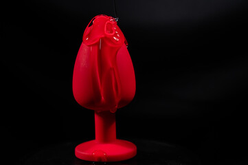 Intimate lubricant pours on a red anal plug on a black background. Copy space. 