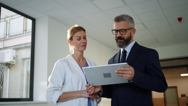 Pharmaceutical sales representative talking with doctor in medical building. Hospital director consulting with healthcare staff.