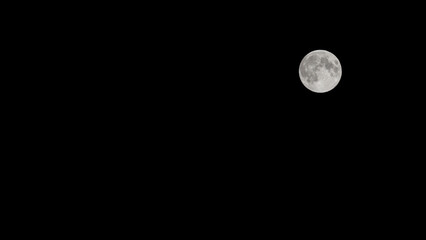 Full moon in the night sky with its lunar craters illuminating the darkness with celestial splendour, isolated on a black background for use as a composite image, stock photo