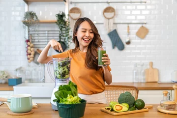 Poster Portrait of beauty healthy asian woman making green vegetables detox cleanse and green fruit smoothie with blender.young girl drinking glass of smoothie, fiber, chlorophyll in kitchen.Diet, healthy. © Art_Photo