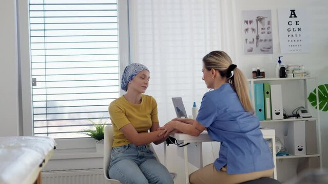 Teenage oncology patient talking with doctor. Oncologist treating teen girl with cancer and provide emotional support, helping her with anxiety and depression.