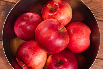 Washed red apples in metal bowl, top view close-up