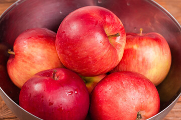 Fototapeta na wymiar Washed red apples in metal bowl close-up