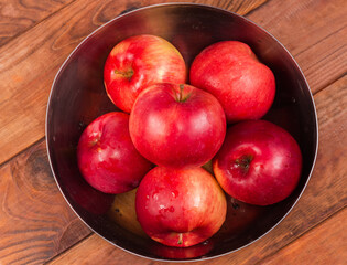 Washed red apples in metal bowl on table, top view