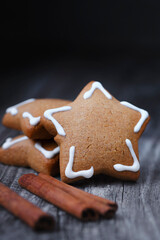 Christmas cookies in the shape of a star with white icing and cinamon on old wooden background. Vertical image.