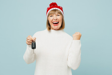 Merry elderly woman 50s years old wears sweater red hat posing hold in hands car key fob keyless...