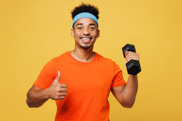 Young fitness trainer instructor sporty man sportsman wear orange t-shirt hold in hand dumbbell...
