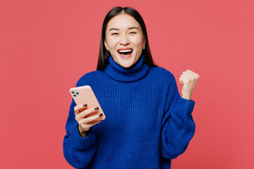 Young smiling happy woman of Asian ethnicity she wear blue sweater casual clothes hold in hand use...